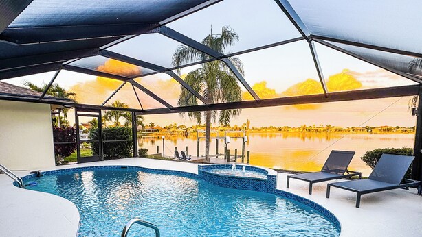 Una piscina interior con vistas a un lago y al atardecer.