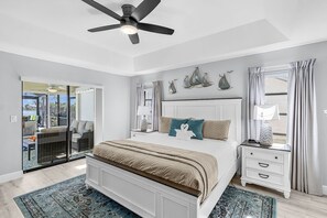 A bedroom with a bed, nightstands, a ceiling fan, and a view through a sliding glass door to an outdoor area. - Quiet & Private Retreat on Thunderbird Lake | Heated Pool, Gulf Access | Sleeps 6 (Cape Coral)