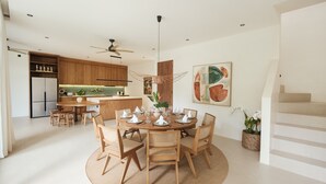 Eine moderne Küche mit Holzausstattung, ein Essbereich mit rundem Tisch und Stühlen sowie eine Treppe.