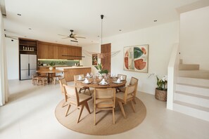 Eine moderne Küche mit Holzausstattung, ein Essbereich mit rundem Tisch und Stühlen sowie eine Treppe.