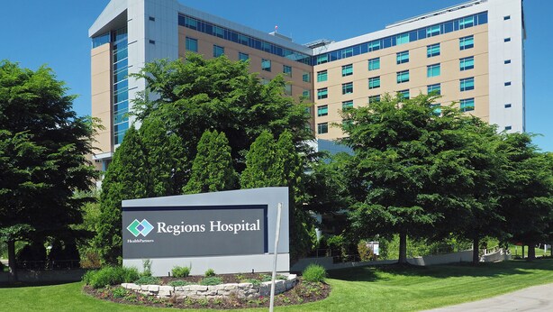 Regions Hospital with a sign in front, surrounded by trees and a clear blue sky. - Bright, cozy & cute in St. Paul by Summit-University with porch and swing chair (Saint Paul)