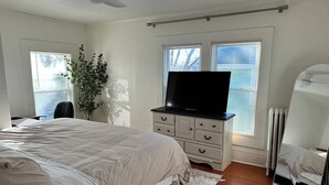 A bedroom with a bed, a dresser, a TV, and a radiator. - Bright, cozy & cute in St. Paul by Summit-University with porch and swing chair (Saint Paul)