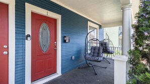 A porch with a red door, a hanging chair, and a white column. - Bright, cozy & cute in St. Paul by Summit-University with porch and swing chair (Saint Paul)