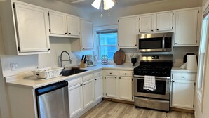 A modern kitchen with white cabinets, stainless steel appliances, and a wooden floor. - Bright, cozy & cute in St. Paul by Summit-University with porch and swing chair (Saint Paul)