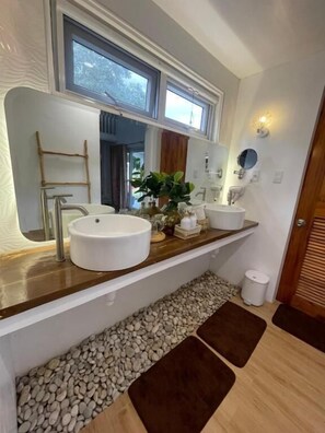 Un bagno moderno con un ampio specchio, due lavabi e un mobile bagno in legno.