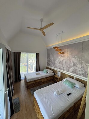 Una camera da letto con due letti, una ventola a soffitto e un'ampia finestra con tende.