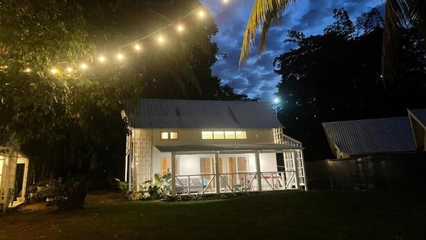 A house with a covered patio, surrounded by trees and a string of lights. - Riomana Villas Resort and Cafe (Cateel)