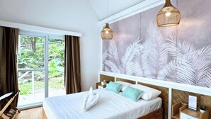 A bedroom with a wooden bed, a ceiling fan, a large window with curtains, a wall-mounted light fixture, and a patterned wall. - Riomana Villas Resort and Cafe (Cateel)