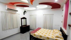 A bedroom with a bed, a dresser, a mirror, and a ceiling with recessed lighting.
