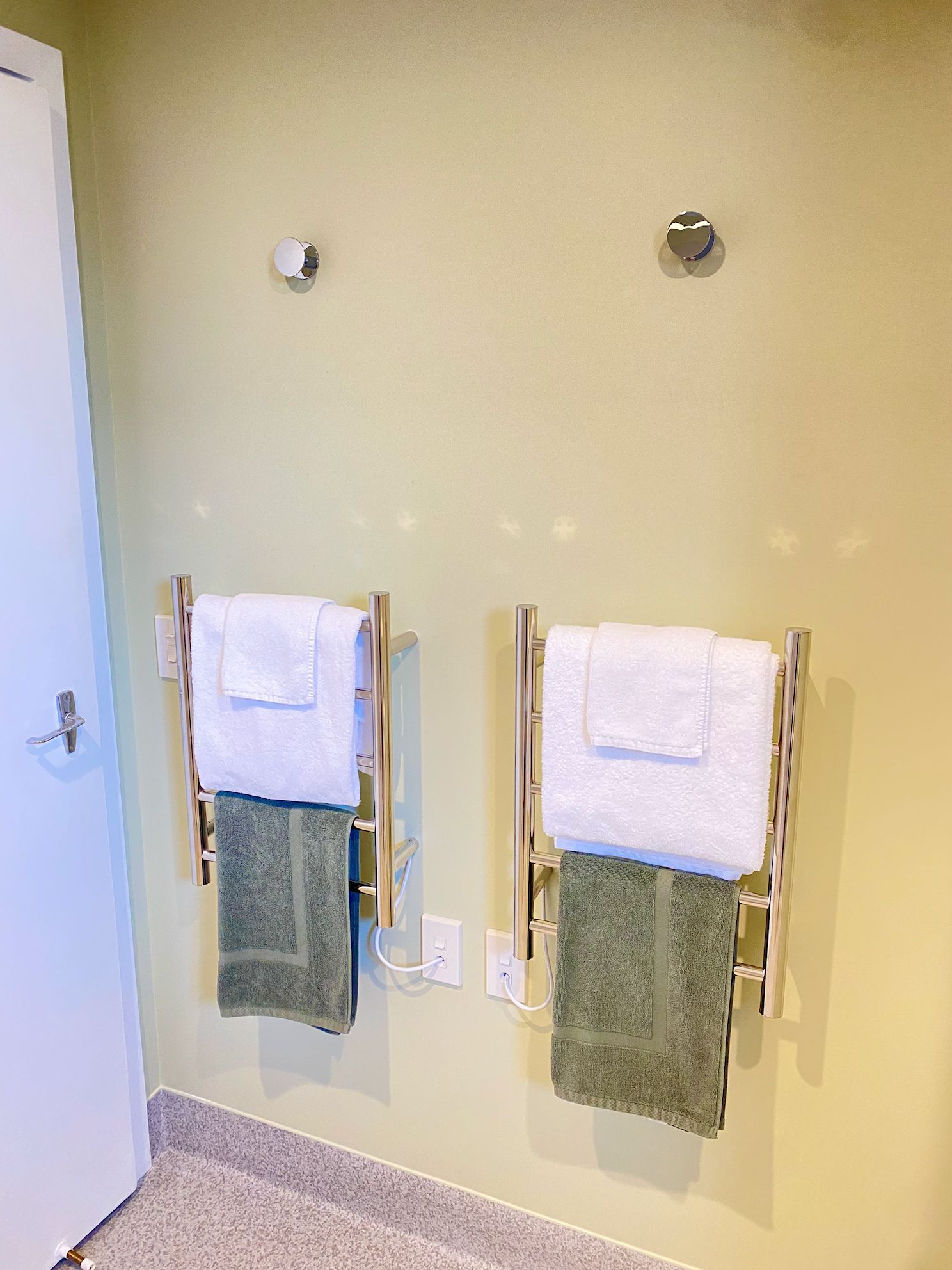 A bathroom with two towel racks, each holding a white and a green towel.