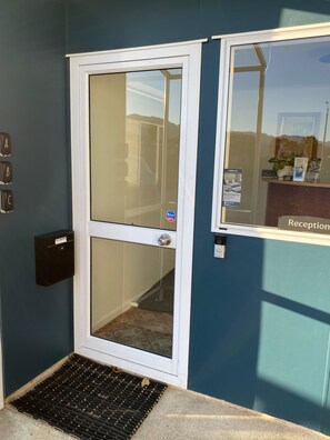 A hotel entrance with a reception desk, a mail slot, and a door with a peephole.