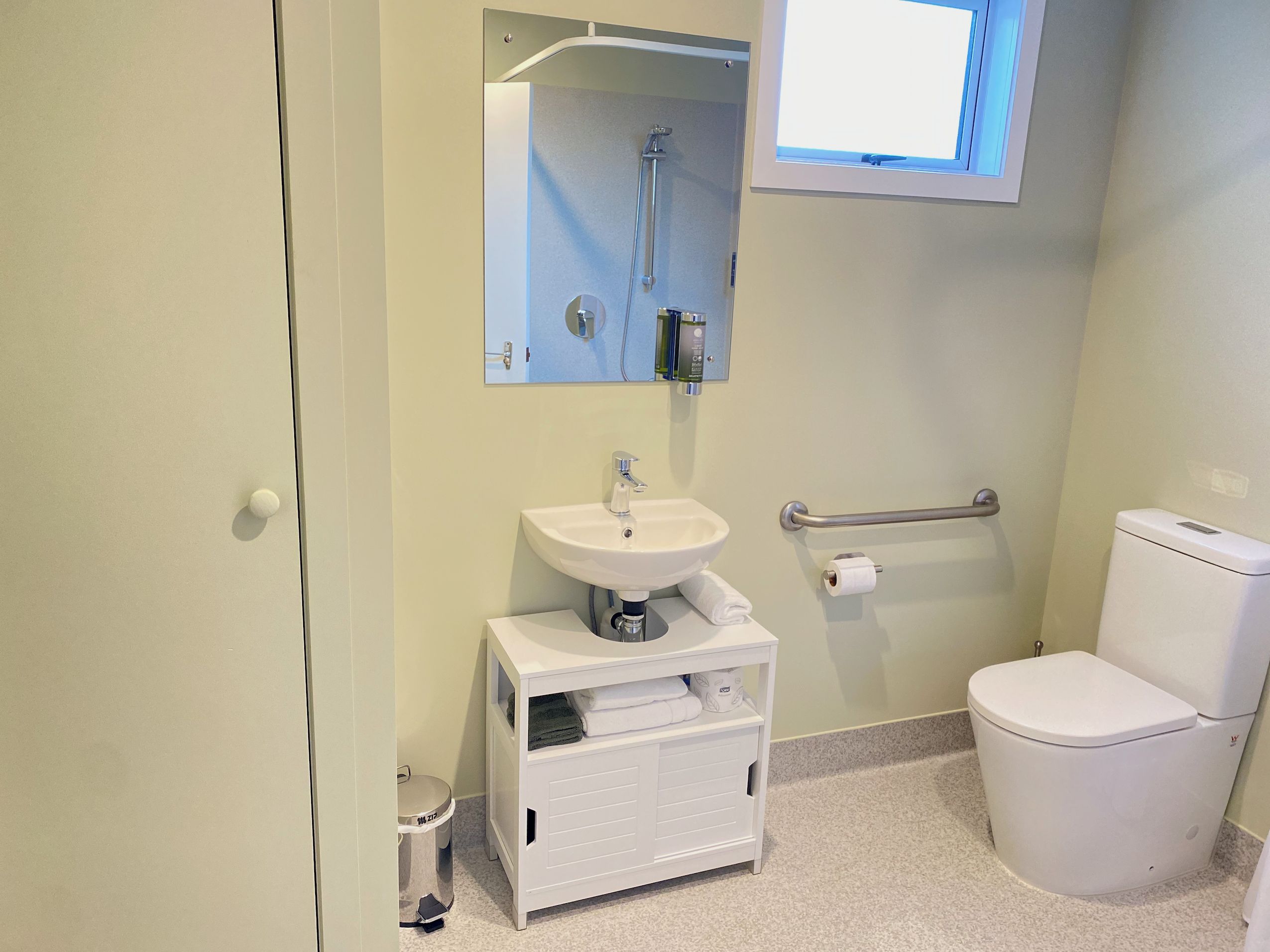 A bathroom with a white sink, toilet, and a mirror above the sink.