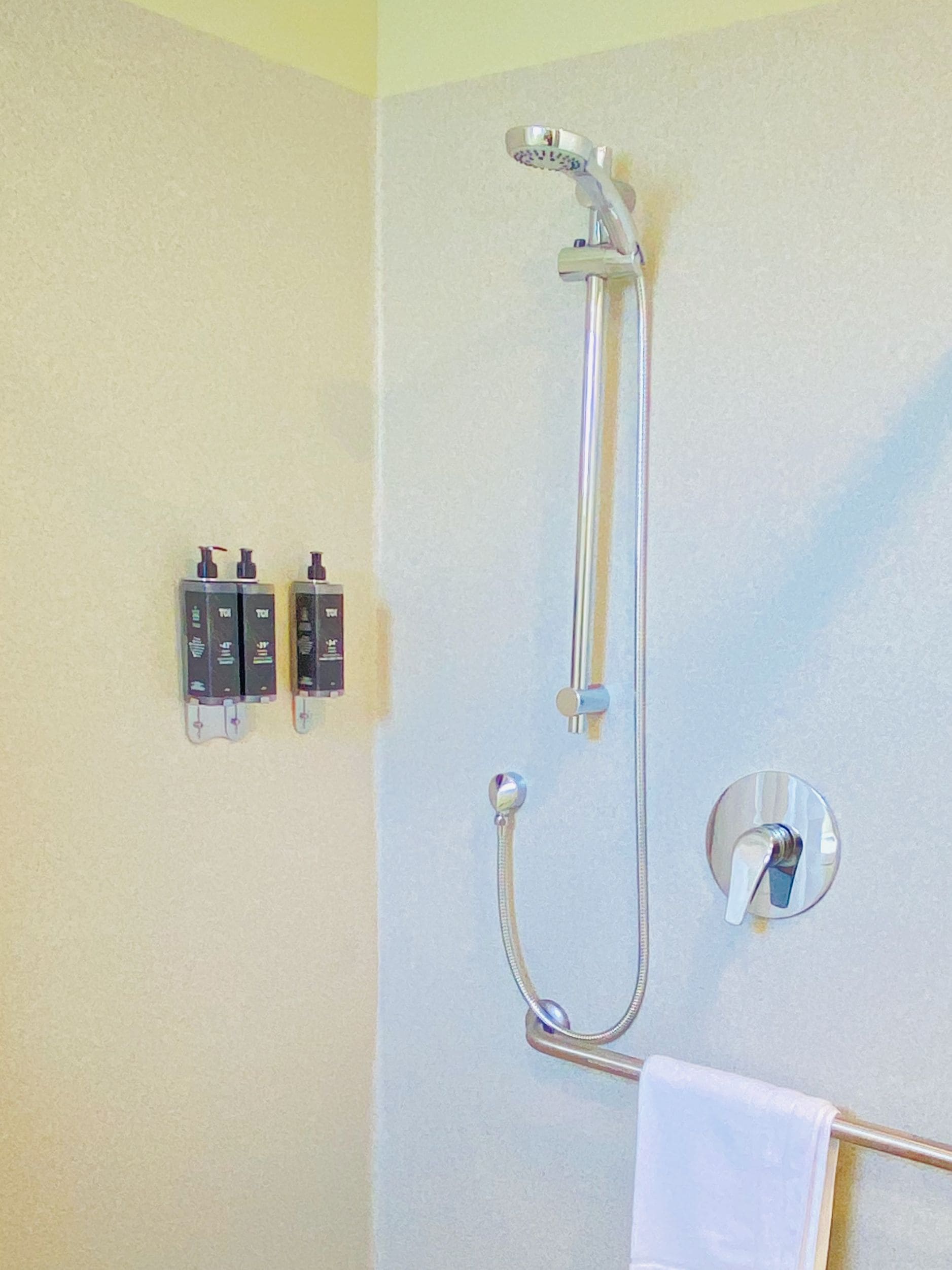 Una ducha con cabezal de ducha manual y panel de control en la pared.
