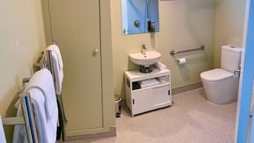 A bathroom with a toilet, sink, towel rack, and a shower area.