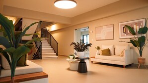 Een ruime woonkamer met een trap, een witte bank en verschillende potplanten.