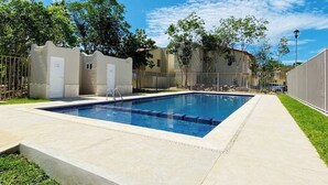 A rectangular swimming pool with a ladder, surrounded by a concrete deck and a metal fence. - Cancun - Next to the Sanctuary Maria untying of knots (Cancún)
