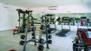 A gym with various exercise equipment, including a squat rack, dumbbells, and treadmills. - Cancun - Next to the Sanctuary Maria untying of knots (Cancún)
