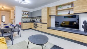 Een moderne keuken met houten kastjes, een inbouwoven en een groot raam met uitzicht op een woonruimte.