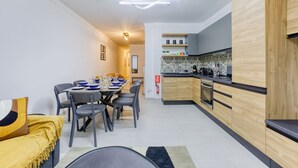 Een moderne keuken met houten kastjes, een eethoek met een tafel voor vier personen, en een klein keukenhoekje.