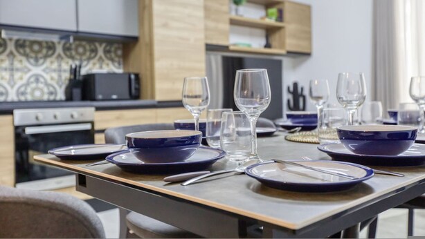 Een moderne keuken met een eettafel voor zes personen, met blauwe borden en heldere glazen.