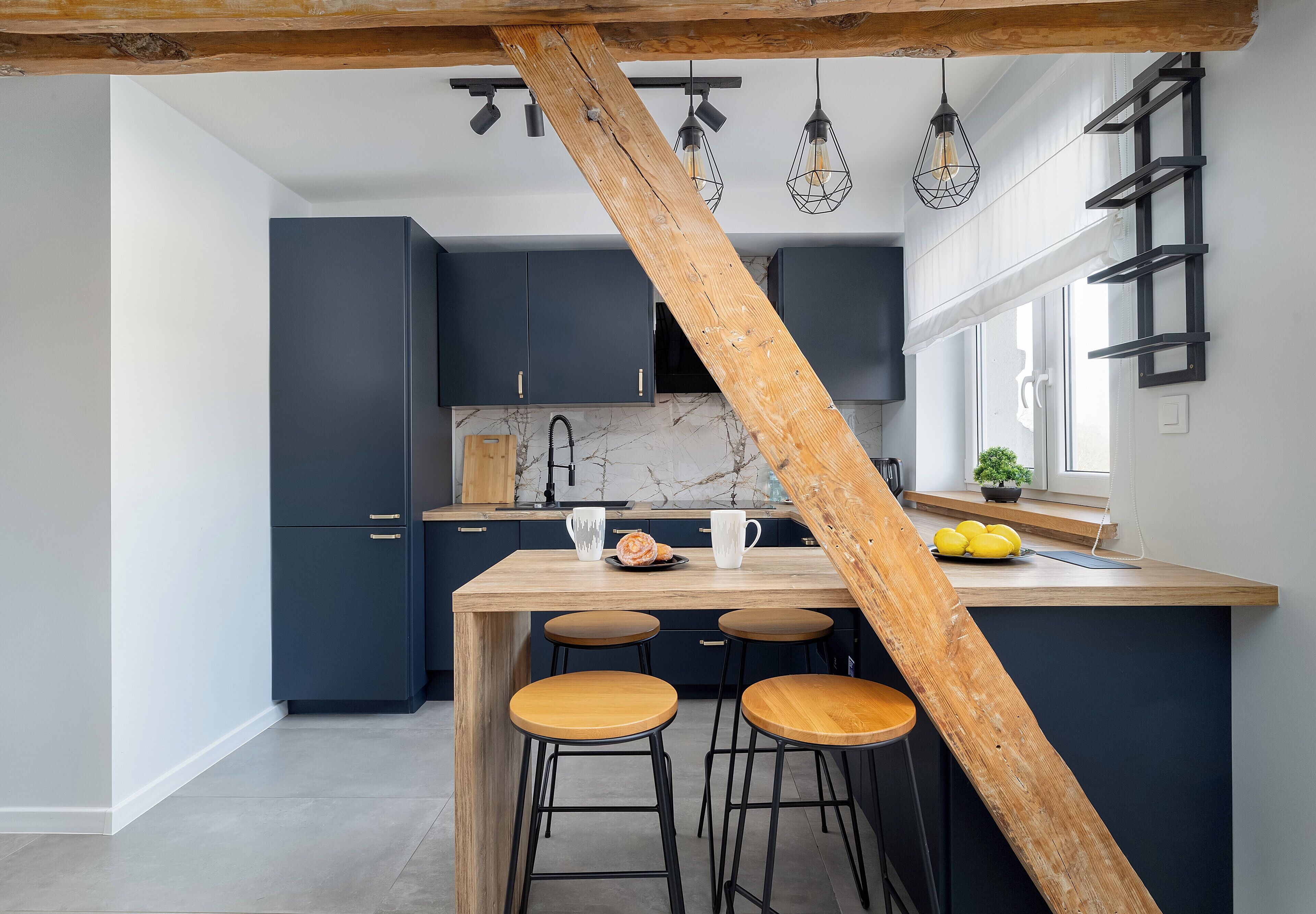 A kitchen with dark blue cabinets, a wooden island with stools, and pendant lights.