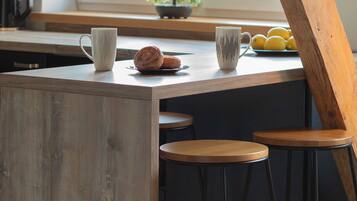 A kitchen counter with a coffee maker, a mug, a plate with lemons, and a small plant.