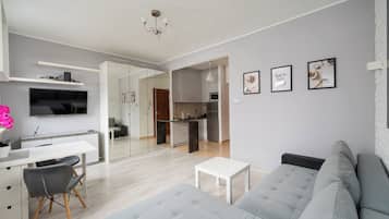 Una sala de estar moderna con un sofá gris, una mesa de centro blanca y un televisor montado en la pared.