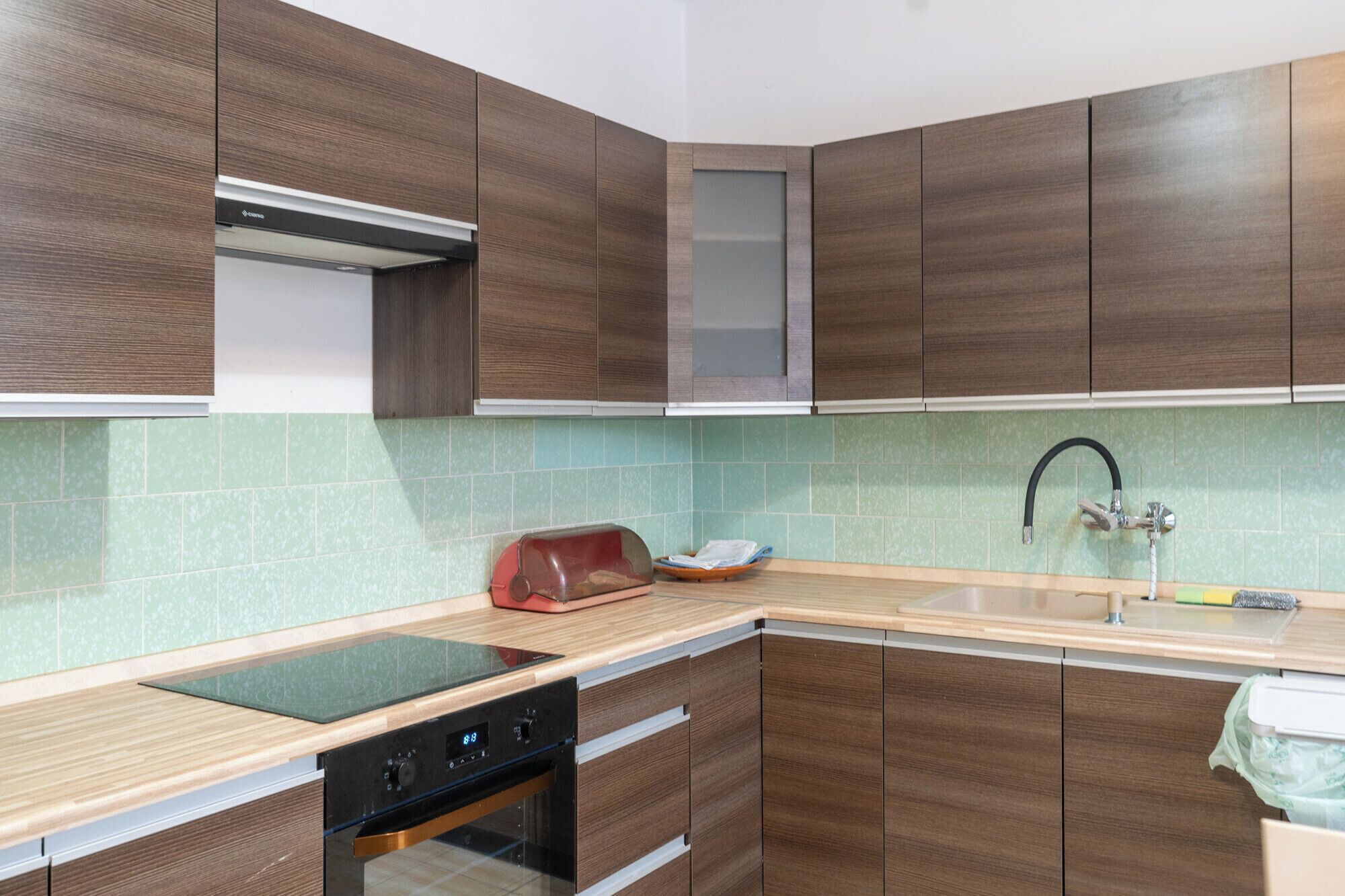Une cuisine moderne avec des meubles en bois, un four encastré et un évier en acier inoxydable.