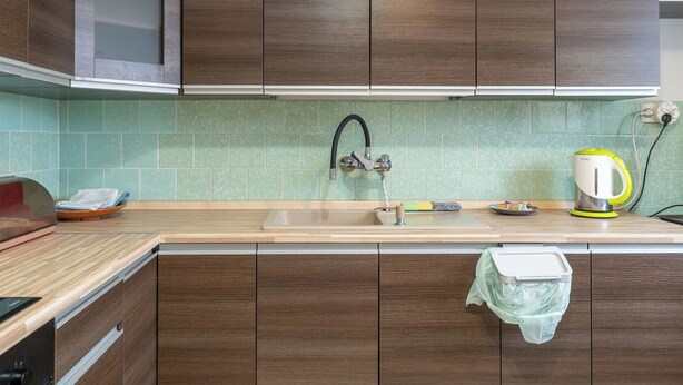 Eine Küche mit Holzausstattung, einem Spülbecken, einem Wasserkocher und einem Mülleimer.