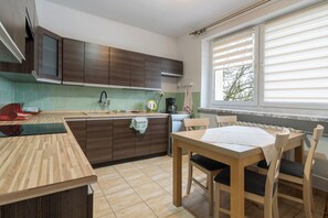 Une cuisine moderne avec des meubles de rangement en bois, un plan de travail et un coin repas comprenant une table et des chaises.