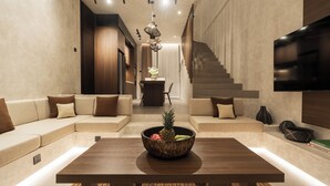 A modern living room with a wooden coffee table, a sofa, and a staircase. - Villa Fresko 5 by Alfred in Bali (Munggu)