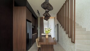 A modern dining area with a wooden table, chairs, and a vase of flowers. - Villa Fresko 5 by Alfred in Bali (Munggu)