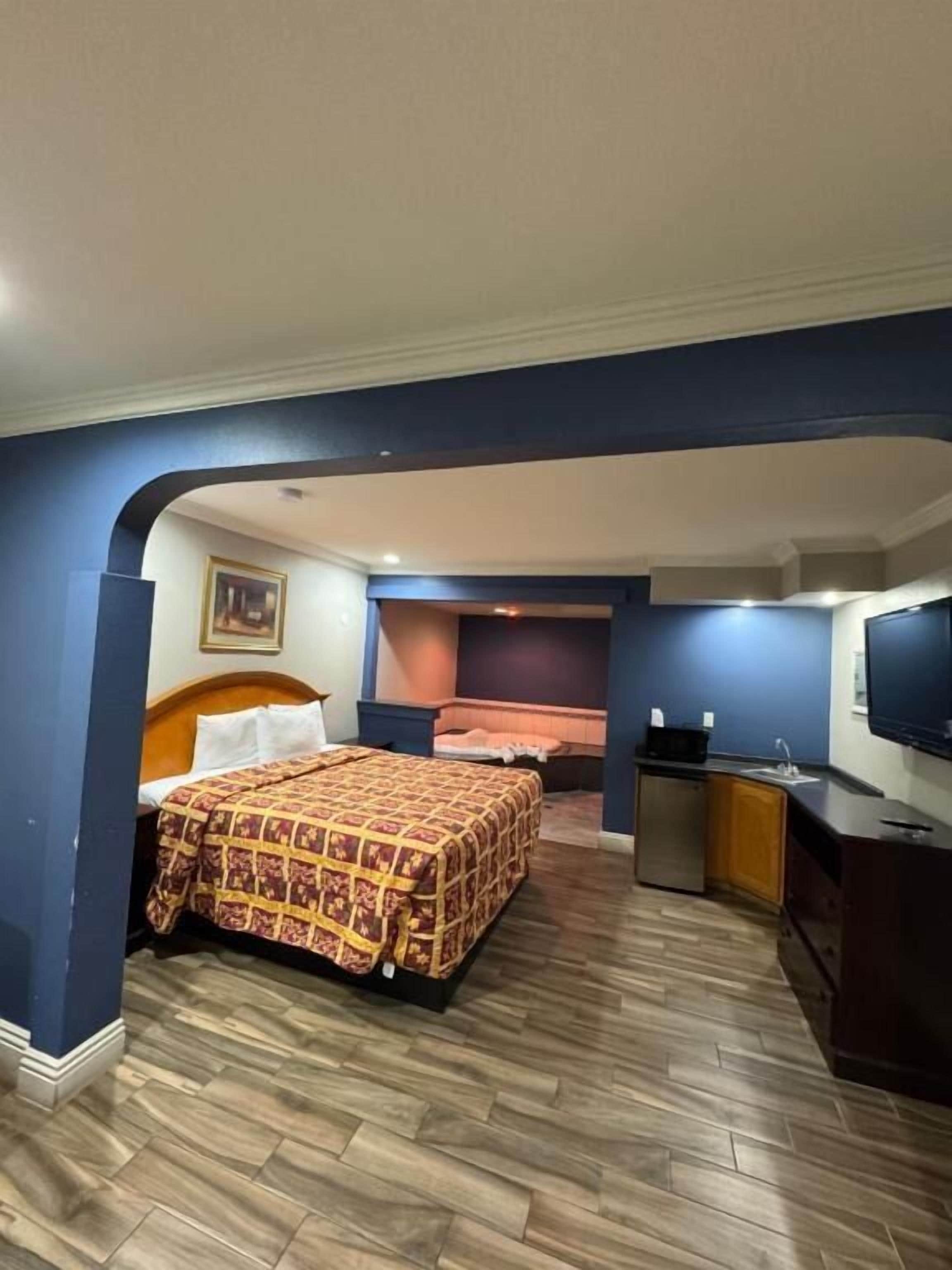 Een hotelkamer met een bed, een kitchenette en een televisie.