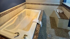 A bathroom with a large bathtub, a sink, and a shower area. - Sunset inn &Suites (Gardena)