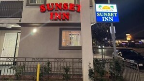 A Sunset Inn signboard with palm trees and a sunset, indicating a beach theme. - Sunset inn &Suites (Gardena)