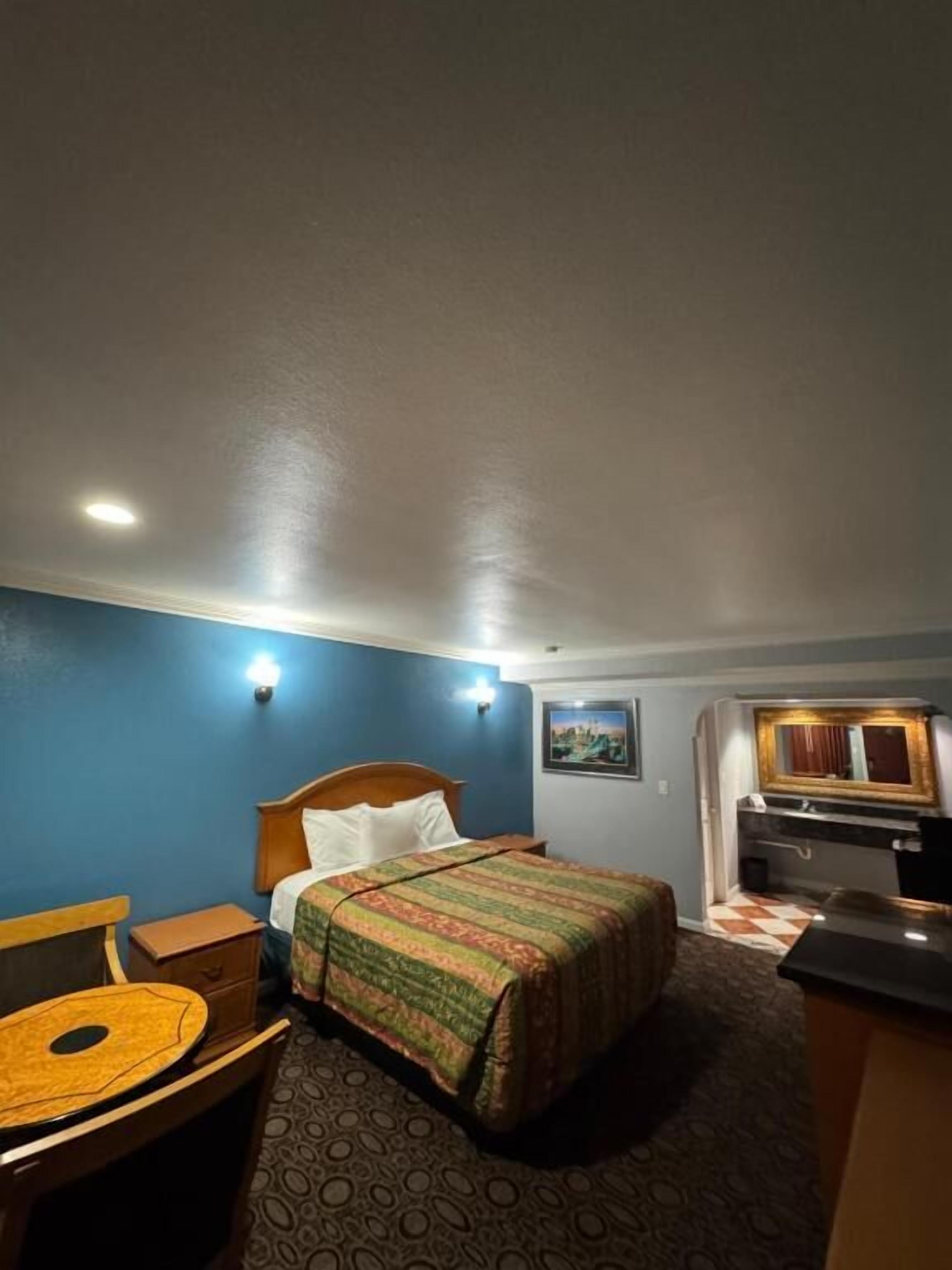 A hotel room with a bed, a desk, a chair, a television, and a picture on the wall.