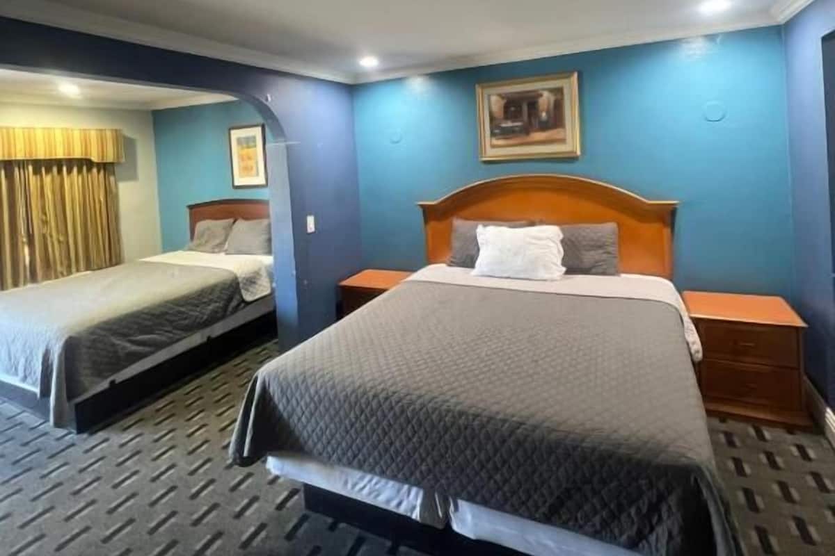 Habitación de hotel con dos camas, cabecero de madera, un cuadro en la pared y alfombra estampada.