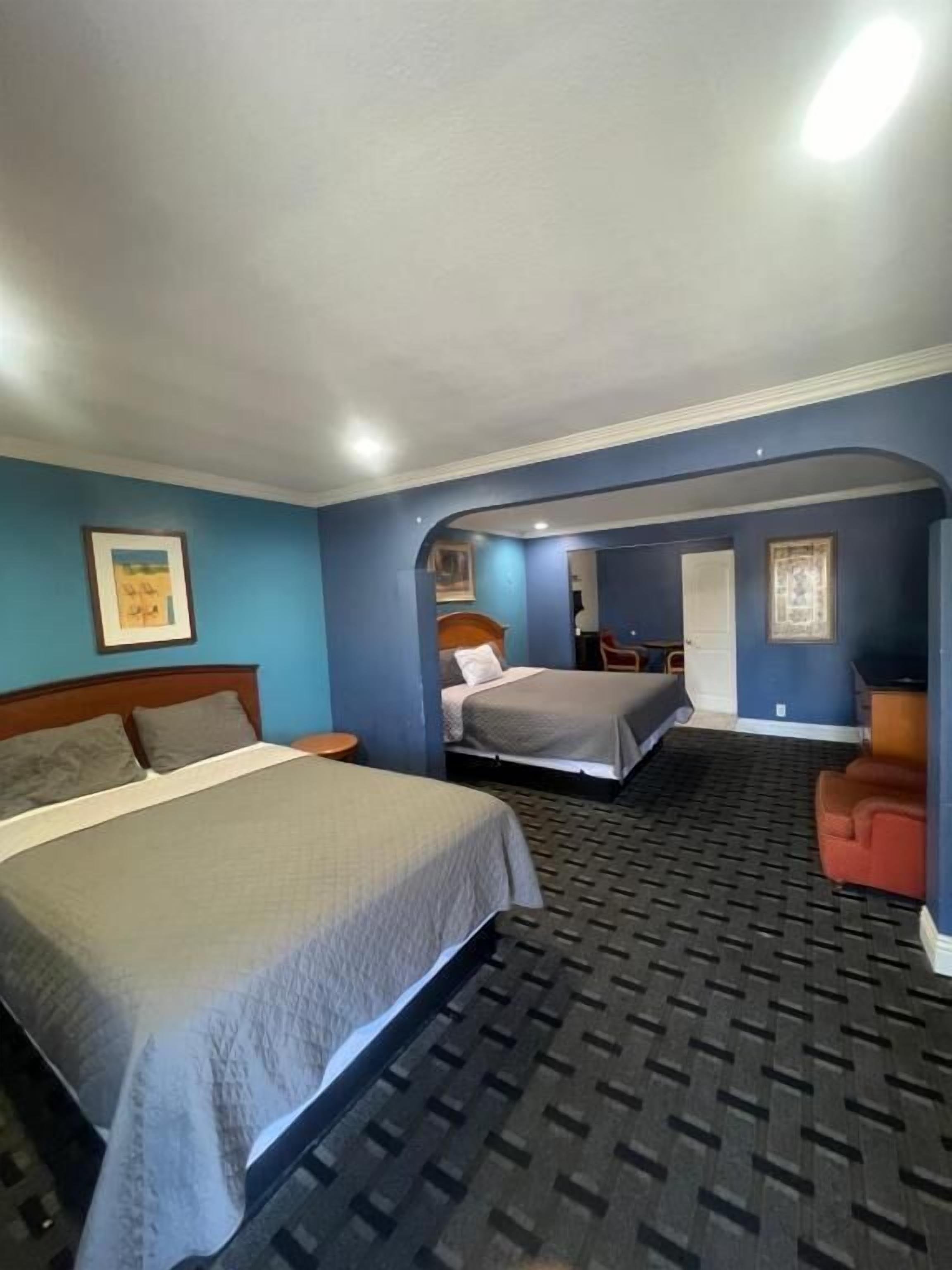A hotel room with a large bed, a smaller bed, a desk, and a chair.