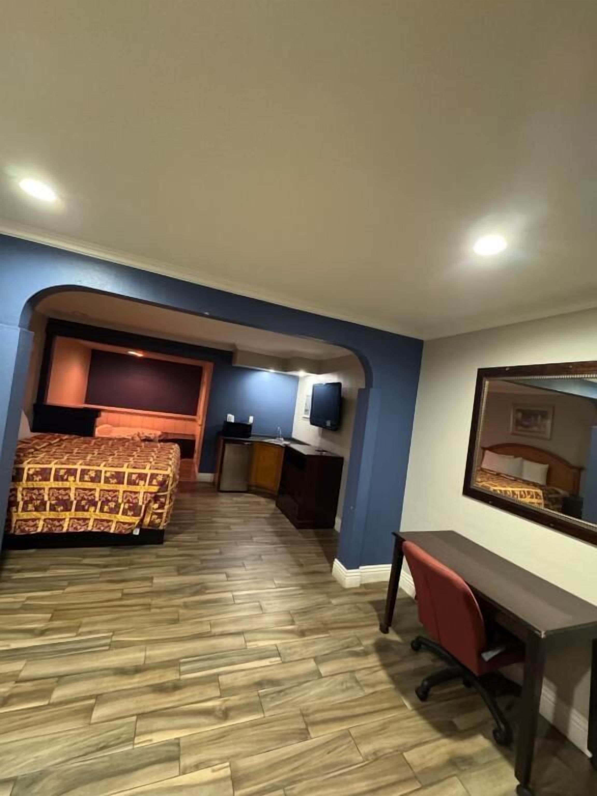 A hotel room with a bed, desk, chair, and a television on the wall.