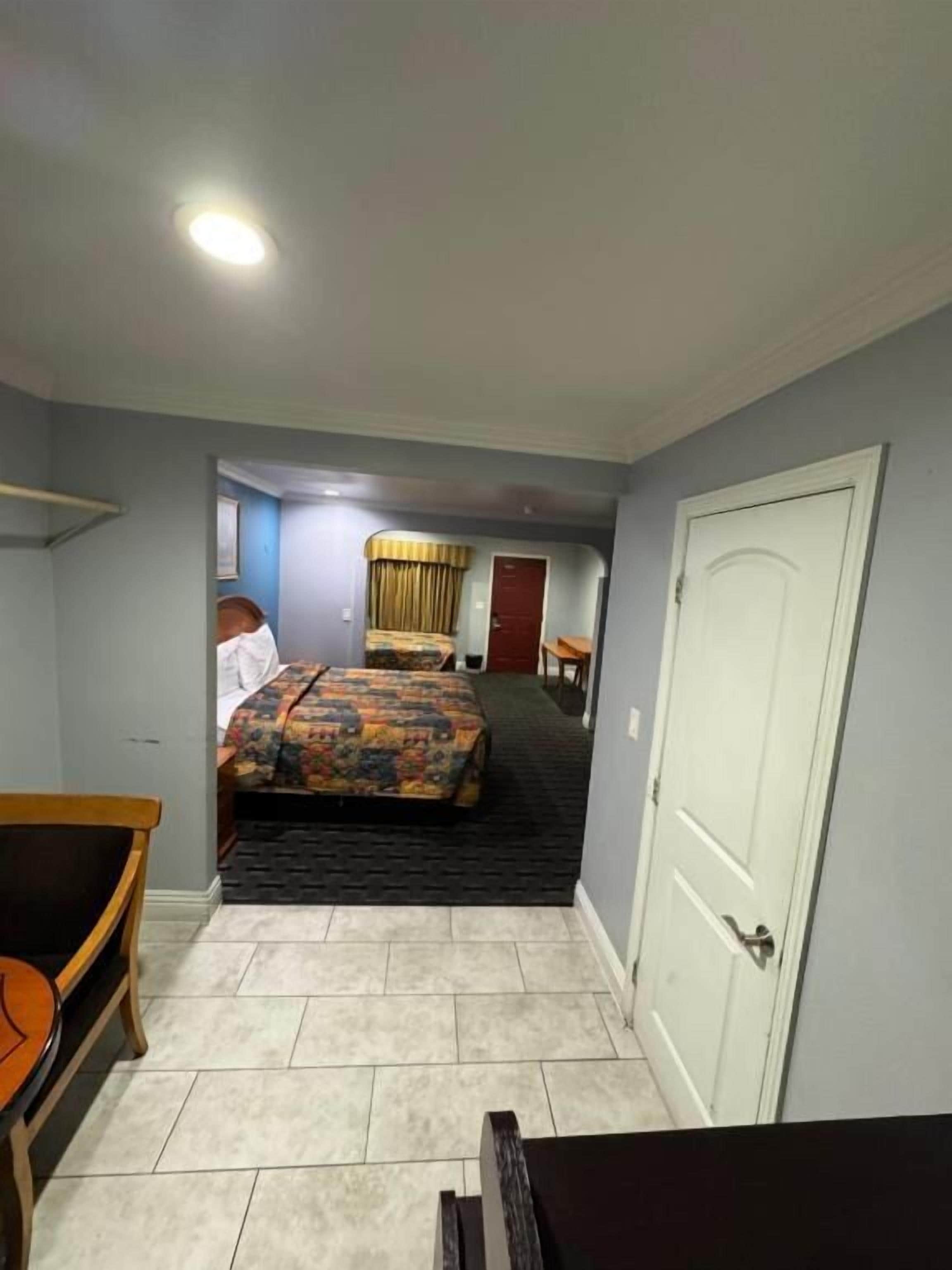 Una habitación de hotel con una cama, una silla, un escritorio y una puerta.