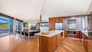 A modern kitchen with wooden cabinets, stainless steel appliances, and a large island. - Fisherman's Rest - Your Perfect Couple’s Retreat (Port Fairy)
