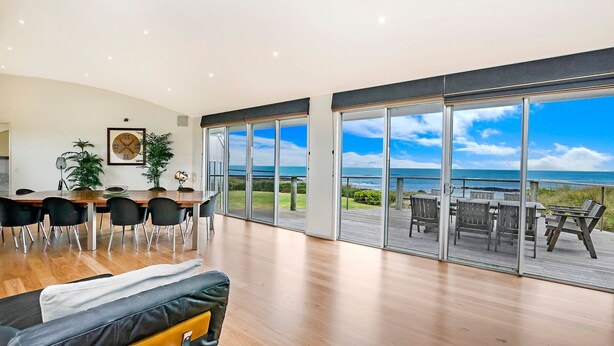 A spacious living area with a large sliding glass door leading to a balcony with a view of the ocean. - Fisherman's Rest - Your Perfect Couple’s Retreat (Port Fairy)