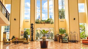 Un vestíbulo espacioso con techos altos, amplias ventanas y una exhibición floral en el centro.