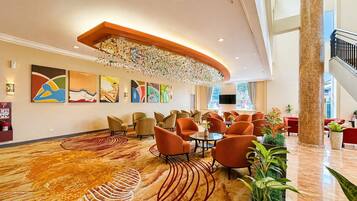 Un hall de hotel de diseño moderno, con una gran lámpara de araña, varias zonas de estar y obras de arte en las paredes.