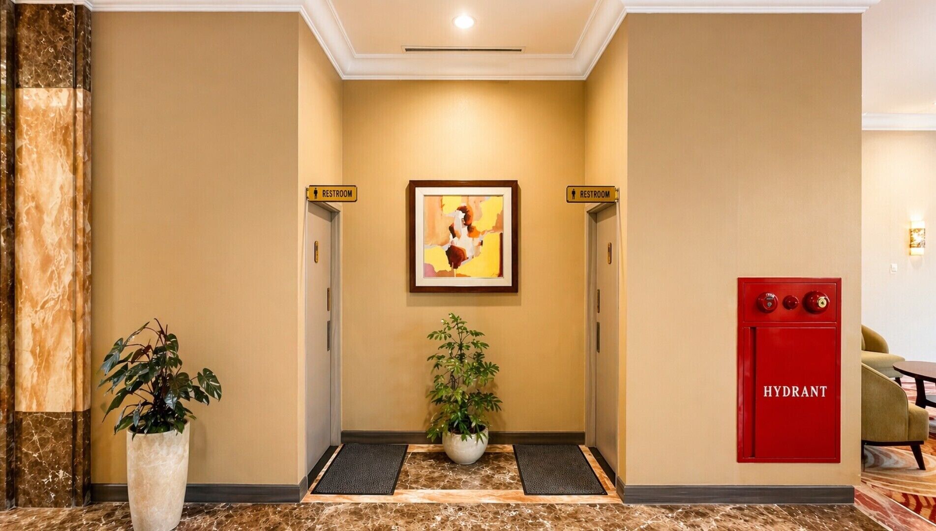 A hotel lobby with a marble floor, a potted plant, a painting, and a red hydrant.