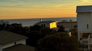 Un quartier résidentiel situé sur la côte, avec des maisons et une vue sur l’océan au coucher du soleil.