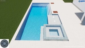 Une piscine rectangulaire à l’eau d’un bleu limpide, entourée d’une terrasse carrelée de blanc et d’une pelouse.