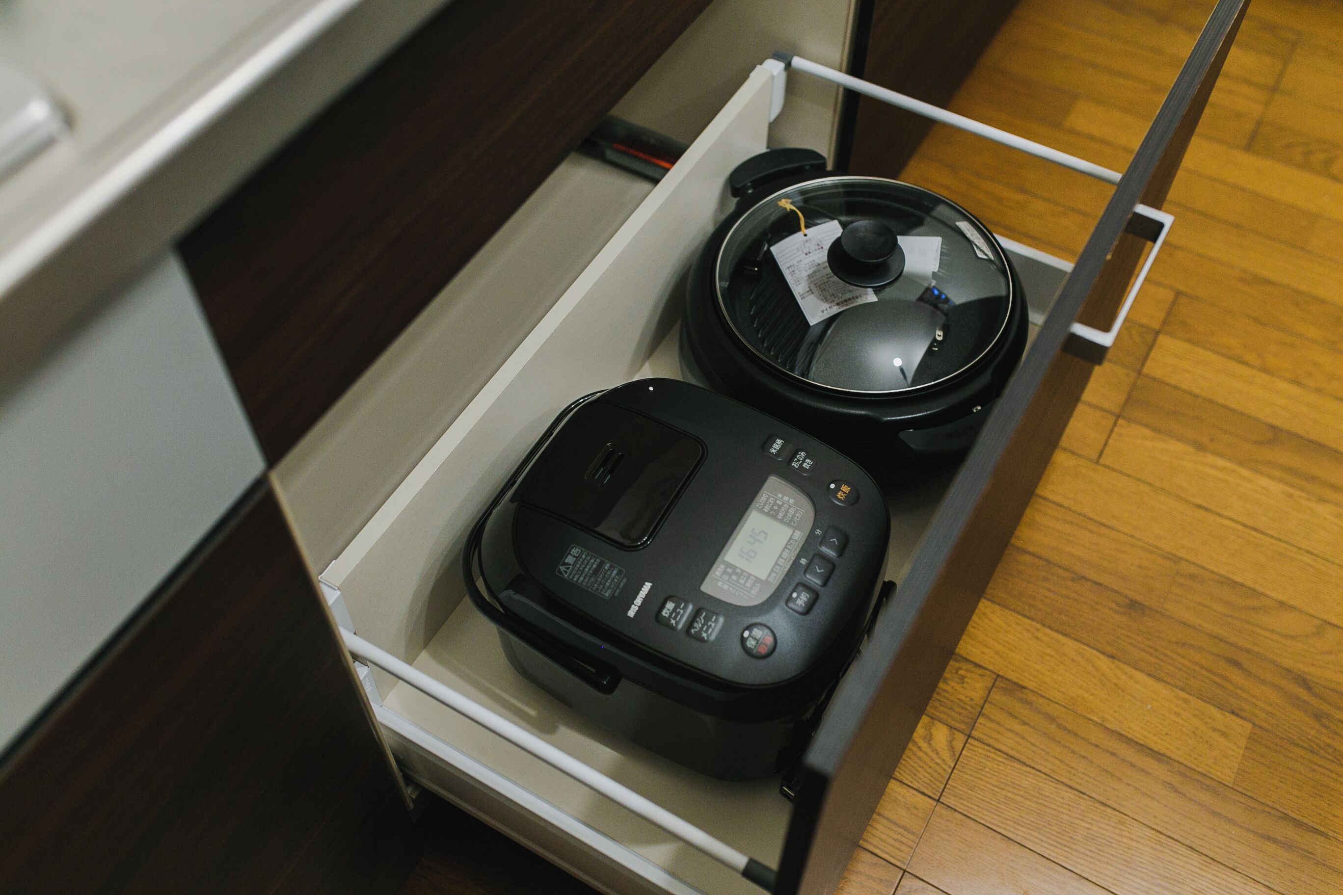 A kitchen drawer containing a rice cooker and a slow cooker.