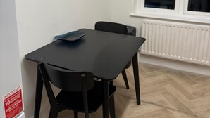 A small room with a black table and two chairs, a white radiator, and a window with blinds. - Wonderful 1-bed apt East London central (London)