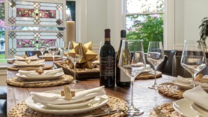 A dining table set with plates, cutlery, and wine glasses, with a bottle of wine and a candle. - Gorgeous 1902 Craftsman-EV Charger-Lush Grounds-Walk to Main Street-Dogs OK (Walla Walla)